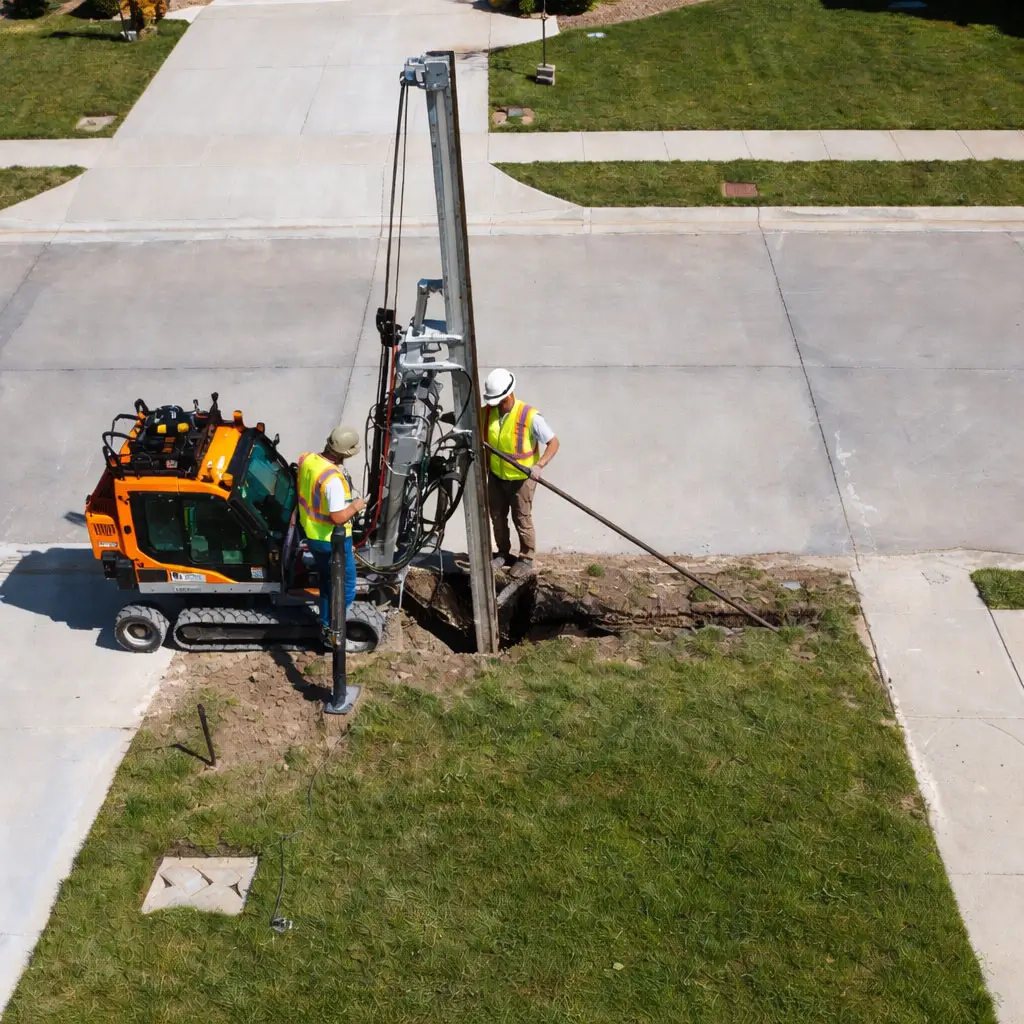 Trenchless shallow utility installation beneath a residential driveway and landscaped area